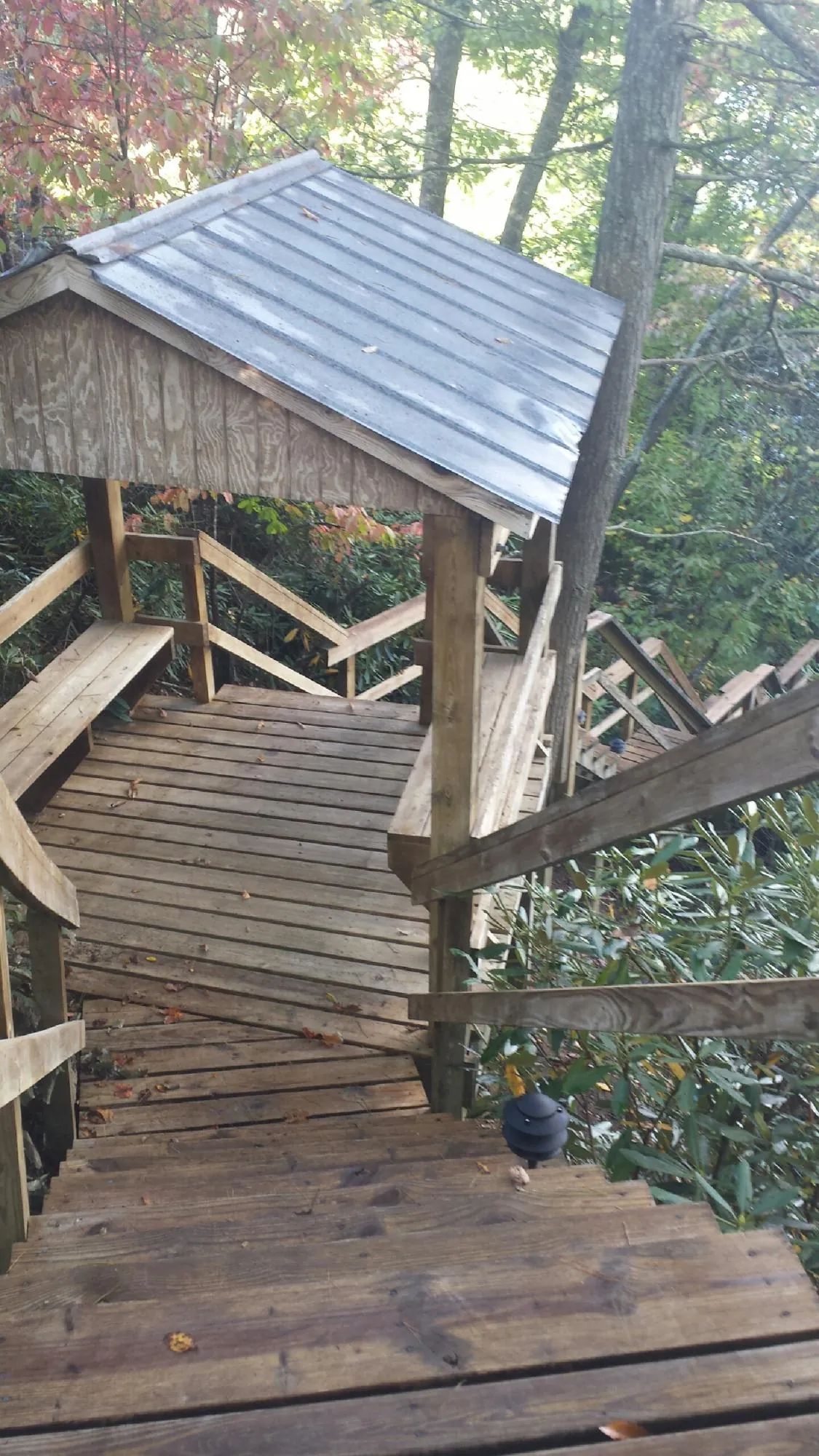 Metal roofed shelter over wooden steps on a wooded walkway — Skylight Repair & Installation work by our crew in Houlton